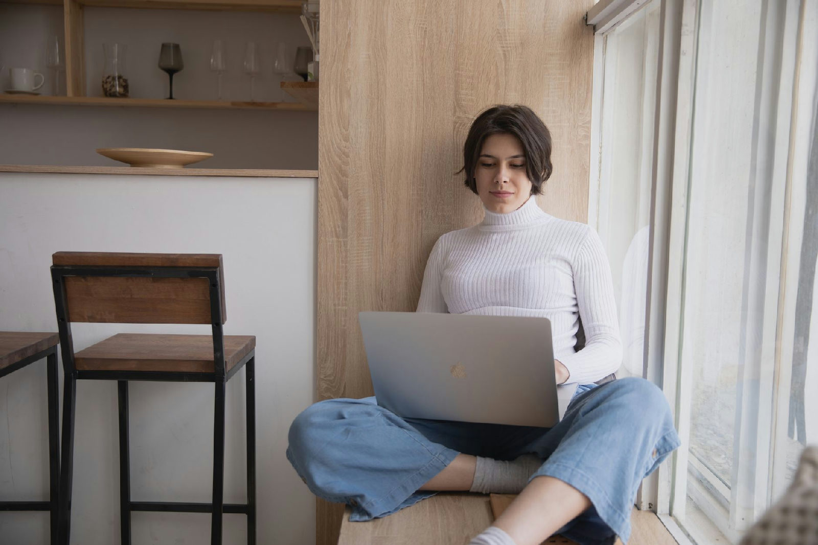 Mulher em um ambiente confortável e iluminado participa de uma sessão de terapia online em seu notebook, demonstrando foco e…