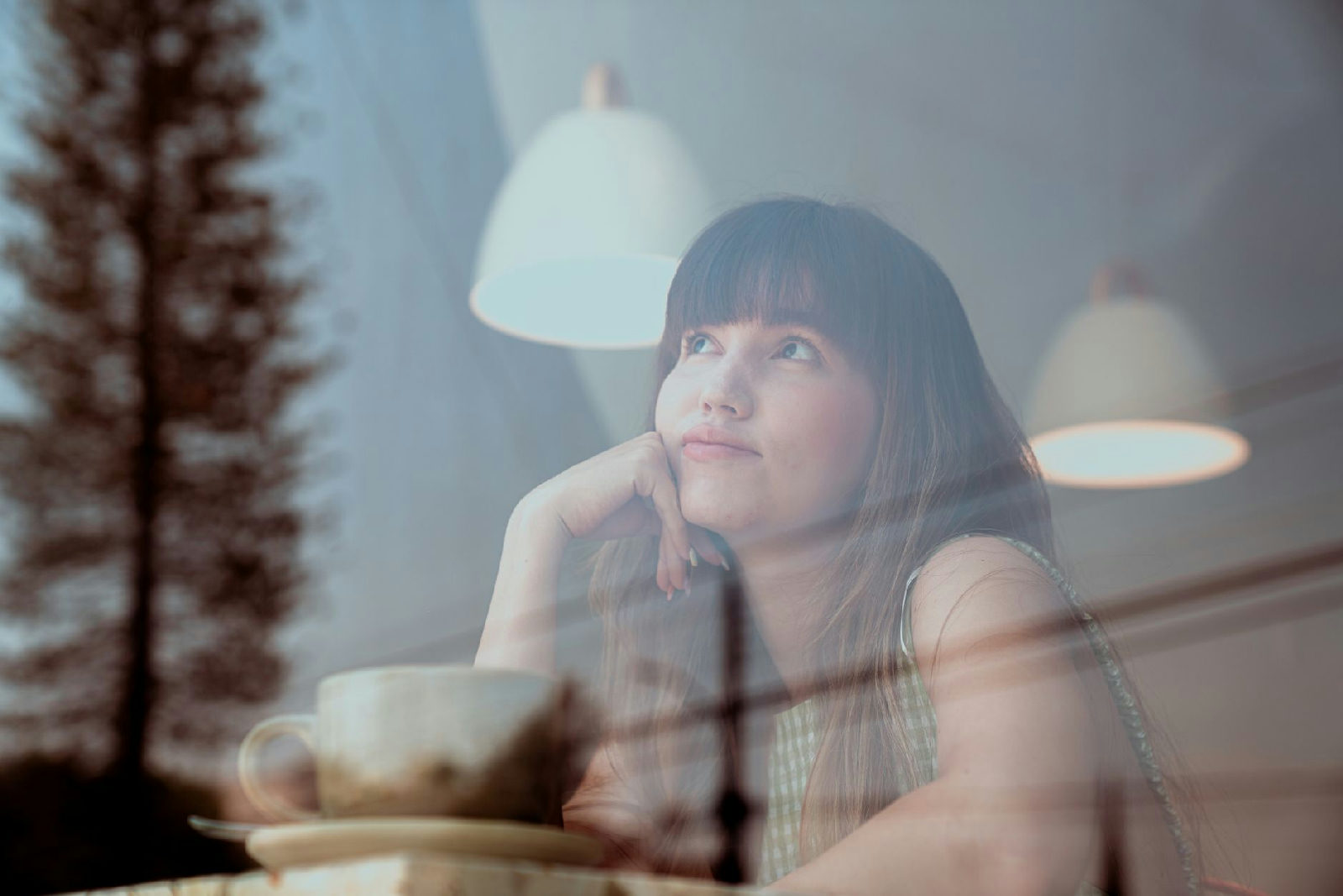 Mulher sentada em um café reflete sobre como a terapia para ansiedade social pode ajudá-la a superar o medo de ser julgada e…