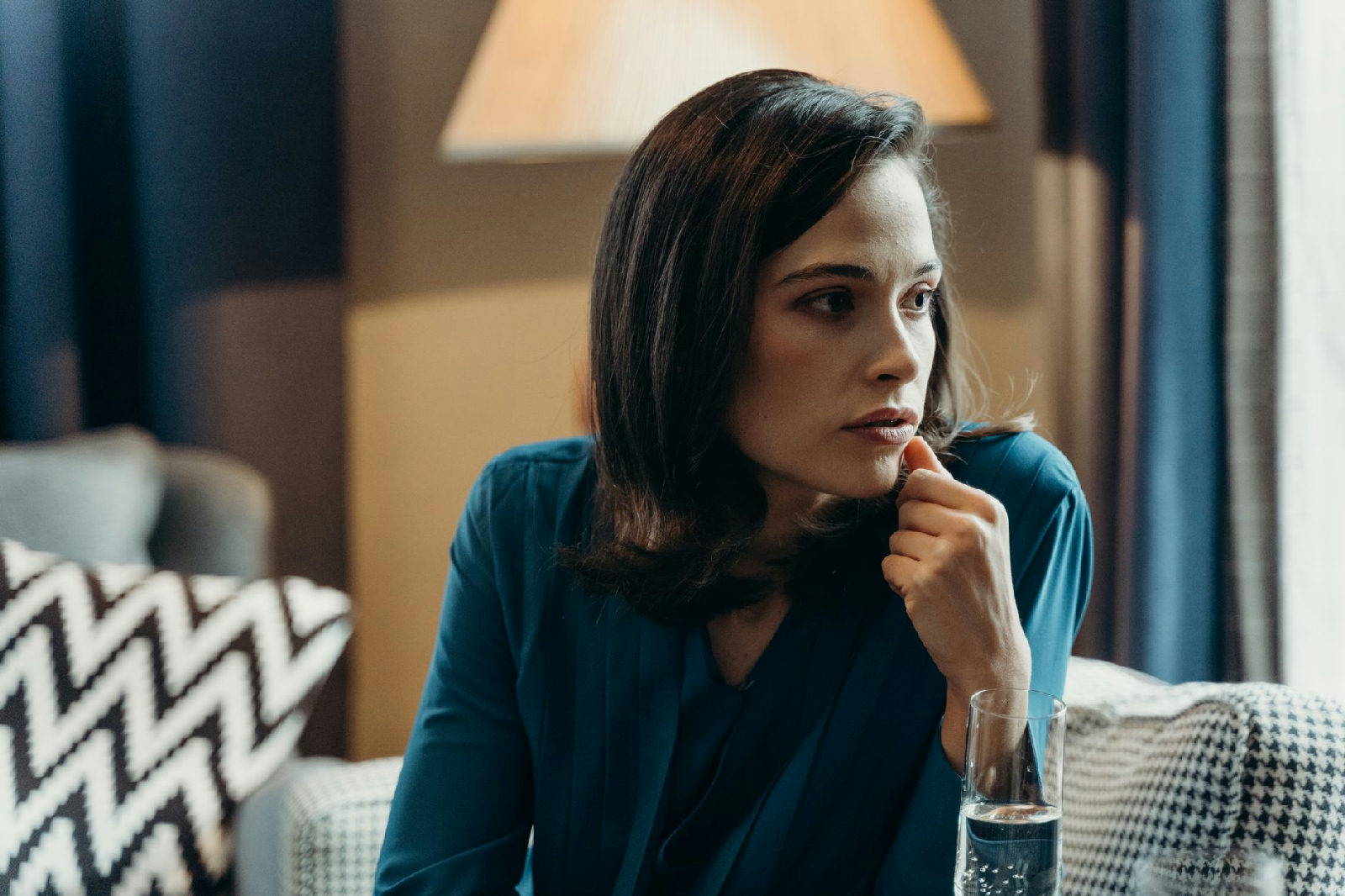 Mulher sentada em um sofá, com olhar pensativo, refletindo sobre os efeitos do gaslighting no relacionamento e como buscar a…