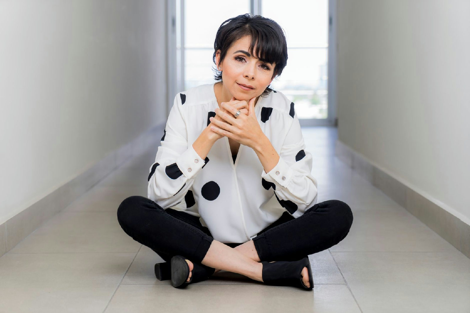 Mulher sentada no chão, refletindo sobre como lidar com a sobrecarga emocional, com uma expressão pensativa mas esperançosa.