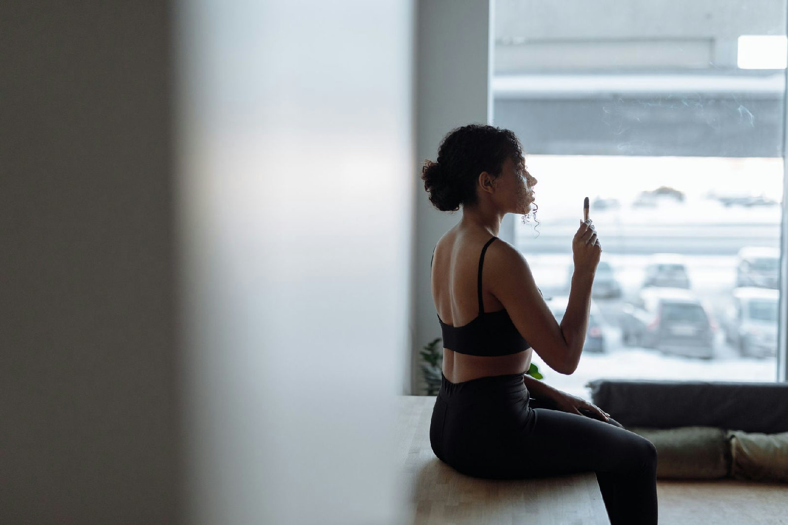 Mulher sentada perto de uma janela praticando técnicas de grounding para controlar uma crise de pânico, com expressão serena.